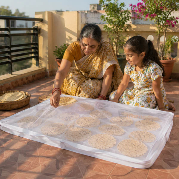 Papad vathal drying cloth spread out with mesh cover for sun drying